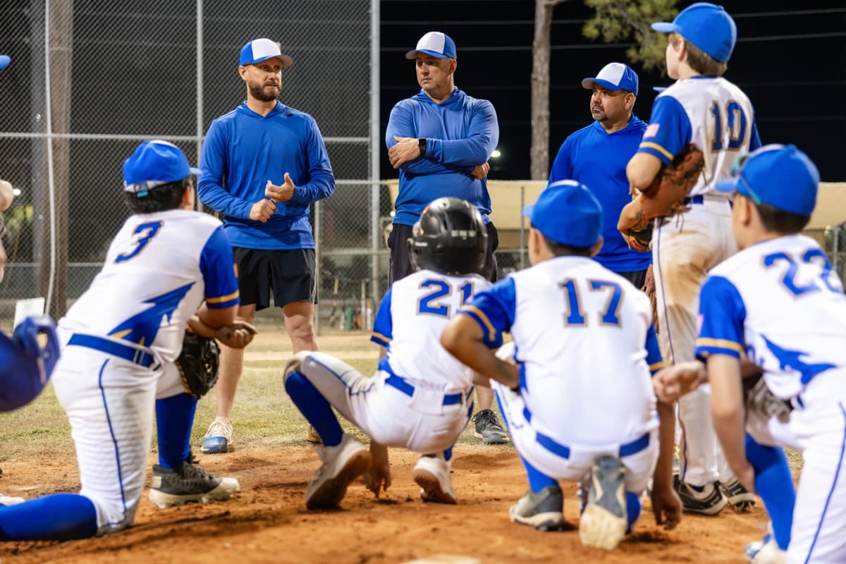 A youth baseball team huddled with their coaches