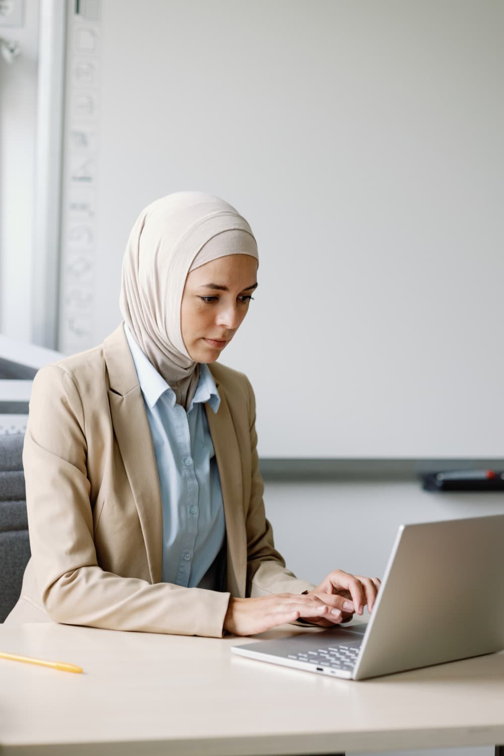An educator working thoughtfully at a laptop